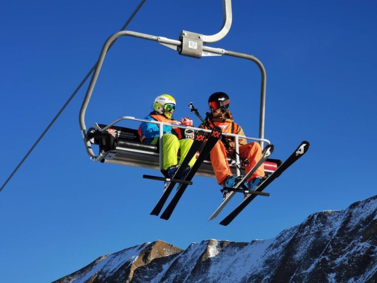 Zwei Teilnehmende mit Skiern auf dem Sessellift in Sörenberg